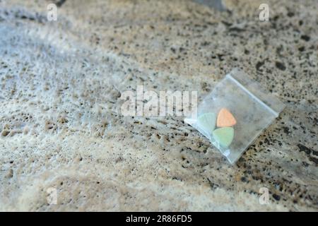 Tesla Ecstasy-Pillen in Orange, Grün und Blau, die wie ein Schild mit dem Tesla Logo geformt sind; 240 Milligramm Freizeit-MDMA oder Molly; Drogen Stockfoto