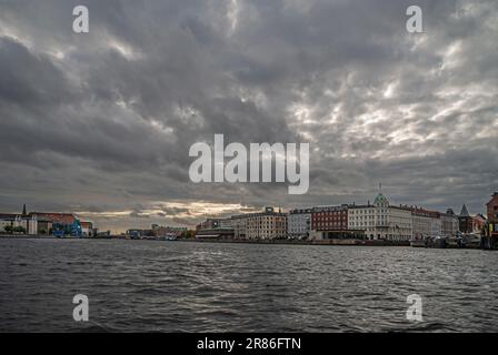 Kopenhagen, Dänemark - 14. September 2010: Weite Sicht über graues Hafenwasser mit Havnepromenade und ihren Gebäuden in der Mitte unter dunkelgrauer Wolkenlandschaft Stockfoto