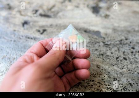 Hand hält Tesla Ecstasy-Pillen in Orange, Grün und Blau, die wie ein Schild mit dem Tesla Logo geformt sind; 240 Milligramm Freizeit-MDMA. Stockfoto