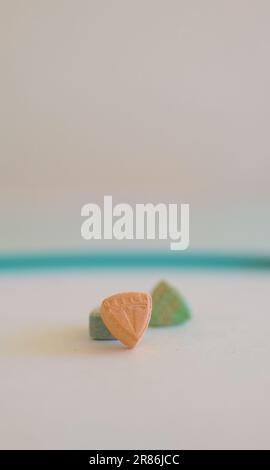 Tesla Ecstasy-Pillen in Orange, Grün und Blau, die wie ein Schild mit dem Tesla Logo geformt sind; 240 Milligramm Freizeit-MDMA oder Molly; Drogen Stockfoto