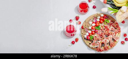 Picknick-Food-Konzept. Korb mit Wein und Baguette, Snacks auf Spießen. Fleisch, Käse, Gemüse, Obst und Blumenstrauß. Hartes Licht, dunkle s Stockfoto