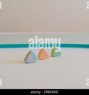 Tesla Ecstasy-Pillen in Orange, Grün und Blau, die wie ein Schild mit dem Tesla Logo geformt sind; 240 Milligramm Freizeit-MDMA oder Molly; Drogen Stockfoto