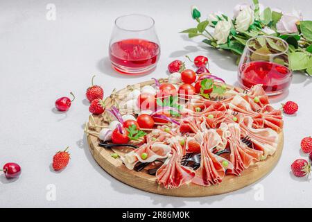 Picknick-Food-Konzept. Korb mit Wein und Baguette, Snacks auf Spießen. Fleisch, Käse, Gemüse, Obst und Blumenstrauß. Hartes Licht, dunkle s Stockfoto