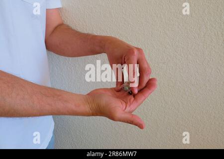 Mann mit Tesla Ecstasy-Pillen-Beutel, Pillen in Form eines Schilds mit dem Tesla-Logo, 240 Milligramm Freizeit-MDMA, Molly, Drogen. Stockfoto