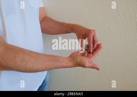 Mann mit Tesla Ecstasy-Pillen-Beutel, Pillen in Form eines Schilds mit dem Tesla-Logo, 240 Milligramm Freizeit-MDMA, Molly, Drogen. Stockfoto