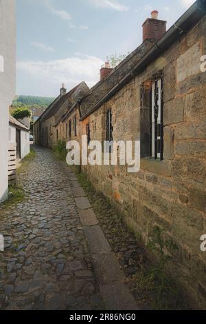 An einem sonnigen Sommertag in Fife, SC, entlang einer engen kopfsteingepflasterten Straße entlang einer stabilen Steinhütte im historischen alten Dorf Falkland Stockfoto