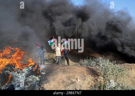 Gaza. 19. Juni 2023. Palästinensische Demonstranten halten die Flagge während eines Protests gegen die Ermordung von fünf Palästinensern in der Nähe des Zauns der Grenze zwischen Gaza und Israel östlich von Gaza-Stadt am 19. Juni 2023. Palästina verurteilte am Montag die Ermordung von fünf Palästinensern durch die israelische Armee und die Verwundung Dutzender anderer während eines Überfalls in der Stadt Dschenin im nördlichen Westjordanland und ihrem Flüchtlingslager. Kredit: Rizek Abdeljawad/Xinhua/Alamy Live News Stockfoto