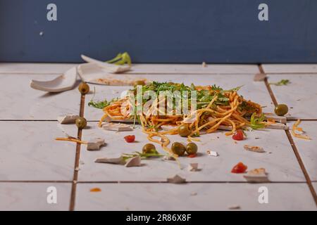 Abgefallener Teller mit Pasta auf dem Küchenboden Stockfoto