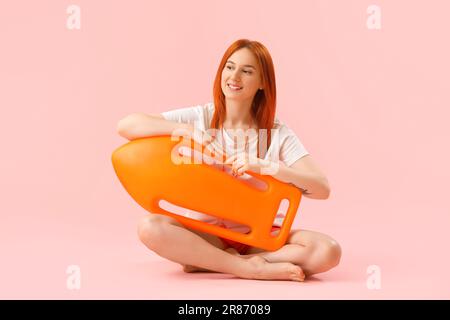 Rettungsschwimmerin mit Rettungsboje auf pinkfarbenem Hintergrund Stockfoto