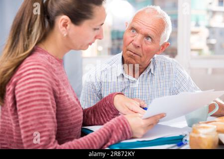 Traurige junge Frau und Vater mit finanziellen Dokumenten zu Hause Stockfoto