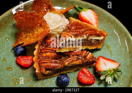 Pekannusskuchen mit Vanilleeis und frischen Beeren Stockfoto