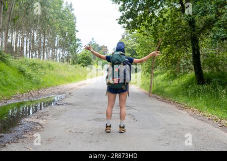 Eine junge Pilgerfrau feiert auf einem Weg des heiligen james. Camino de Santiago. Leistungskonzept Stockfoto