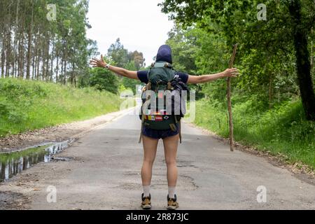 Eine junge Pilgerfrau feiert auf einem Weg des heiligen james. Camino de Santiago. Leistungskonzept Stockfoto