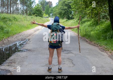 Eine junge Pilgerfrau feiert auf einem Weg des heiligen james. Camino de Santiago. Leistungskonzept Stockfoto