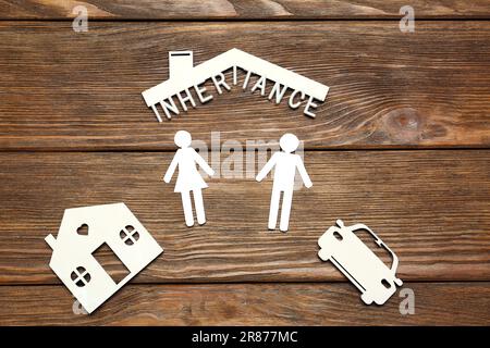 Wortvererbung mit weißen Buchstaben und verschiedenen Ausschnitten auf Holztisch, flach liegend Stockfoto