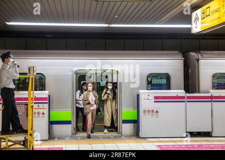 Mitarbeiter des U-Bahnnetzes von Tokio, Zugwächter an einer Station, während Pendler warten, um aus dem Zug auszusteigen, Tokio, Japan, 2023 Stockfoto