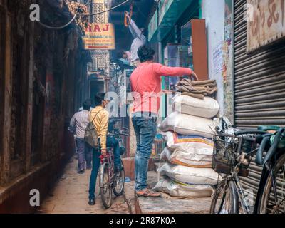 Varanasi, Indien - 11. November 2015. Lokale Händler bereiten sich darauf vor, ihre Geschäfte für den Tag in einer engen Gasse der Stadt zu eröffnen. Stockfoto