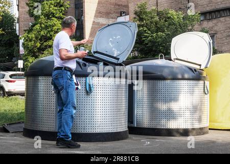 Ein Mann wirft Müll in einen Sortierbehälter auf der Straße. Die Ökologie der Umwelt. Müllrecycling Stockfoto