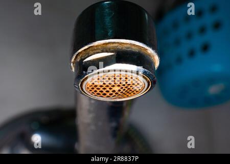 Strahldiffusor in der Wasserhahnnaht. Korrosion und Kalkablagerungen aus Wasser. Dreckiger, alter Wasserhahn im Waschbecken auf verschwommenem Hintergrund Stockfoto