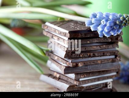 Dekorativer Schokoladenstapel auf Holzbrett mit Blume Stockfoto