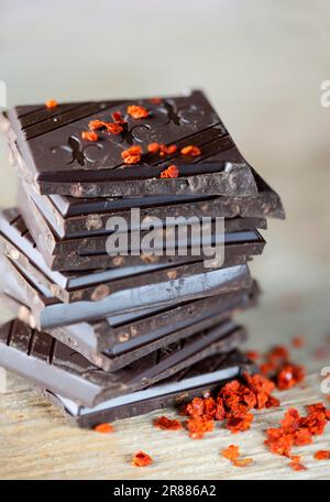Dekorativer Schokoladenstapel auf Holzbrett mit Chiliflocken Stockfoto