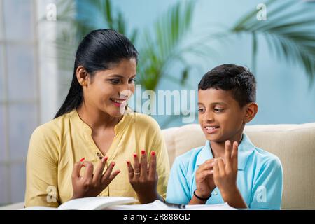 Glückliche indische Mutter, die ihrem Sohn Mathematik-Hausaufgaben zu Hause beibringt - Konzept von Hausunterricht, Nachhilfe und Ausbildung Stockfoto