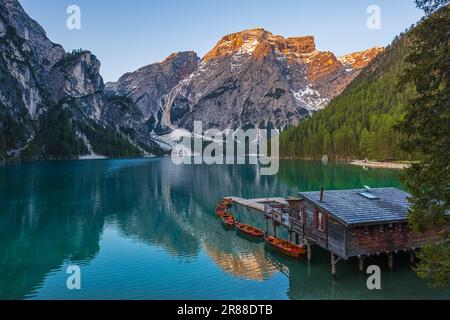 Ein Bild eines frühen Frühlingsmorgens bei Sonnenaufgang am Bootshaus und der berühmten Ruderboote am Pragser Wildsee (Lago di Braies), einem malerischen See i. Stockfoto