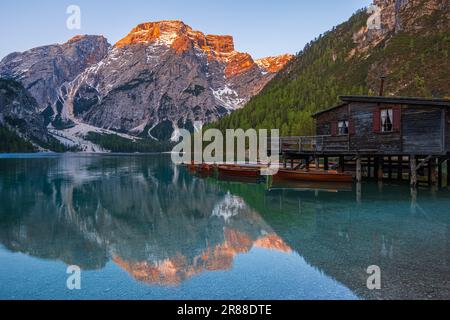 Ein Bild eines frühen Frühlingsmorgens bei Sonnenaufgang am Bootshaus und der berühmten Ruderboote am Pragser Wildsee (Lago di Braies), einem malerischen See i. Stockfoto