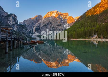 Ein Bild eines frühen Frühlingsvormittags bei Sonnenaufgang am Bootshaus und berühmter Ruderboote am Pragser Wildsee (Lago di Braies), einem malerischen See in diesem Stockfoto