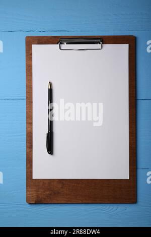 Klemmbrett mit Blatt Papier und Stift auf hellblauem Holztisch, Draufsicht. Platz für Text Stockfoto