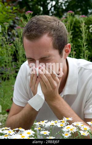 Junger Mann mit Heuschnupfen, Niesen, Niesen, Taschentuch, Allergie, Pollenallergie, Schnupfen, Nasenbluten Stockfoto