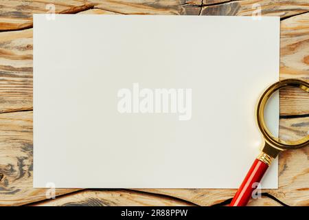 Vergrößerungsglas auf altem Papier auf dunkelbraunem Holz-Backgorund Stockfoto