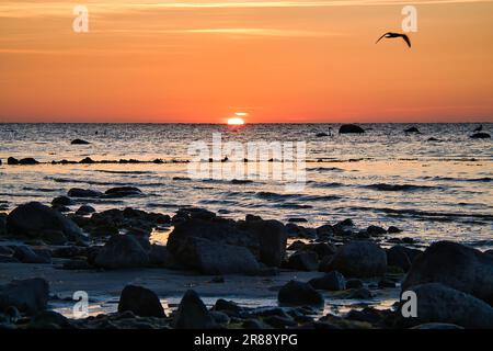 Sonnenuntergang, Steinstrand mit kleinen und großen Felsen vor dem beleuchteten Meer. Lichtwellen. Poelinsel an der Ostsee. Naturfoto von den coas Stockfoto