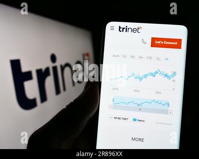 Person, die ein Mobiltelefon mit der Website des US-Outsourcing-Unternehmens TriNet Group Inc. Auf dem Bildschirm vor dem Logo hält. Konzentrieren Sie sich auf die Mitte des Telefondisplays. Stockfoto