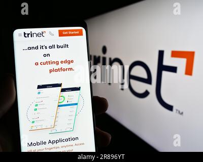Person, die ein Mobiltelefon mit einer Webseite des US-Outsourcing-Unternehmens TriNet Group Inc. Auf dem Bildschirm vor dem Logo hält. Konzentrieren Sie sich auf die Mitte des Telefondisplays. Stockfoto