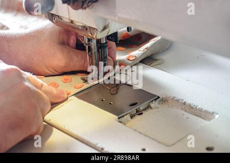 Innenarchitekt, der an einer industriellen Nähmaschine arbeitet, mit Stoff für Polster, Vorhänge oder Innendekoration Kopierraum, ausgewählter Fokus, schmal Stockfoto