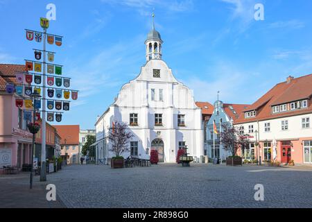 Wolgast, Deutschland, 14. Juni 2023: Rathaus auf dem Marktplatz, Häuser und Mast mit Handwerkssymbolen unter blauem Himmel, historische Altstadt an der Ostsee Stockfoto