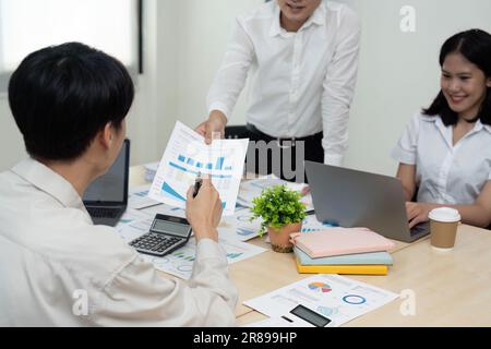 Mitarbeiter des Business Teams, die über die Analyse von Investitionen diskutieren Diagramme und Diagramme, die die Ergebnisse ihrer erfolgreichen Teamarbeit zeigen, indem sie Tastatur eingeben Stockfoto