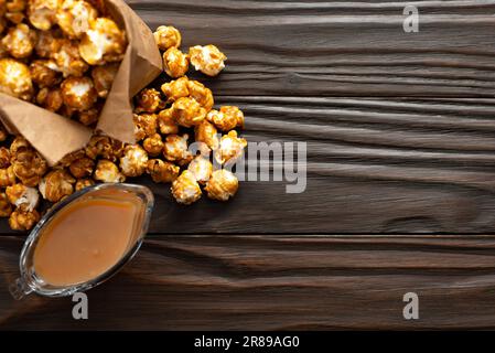 Karamellisiertes Popcorn in Papiertüte auf hölzernen Küchentisch flach legen Stockfoto