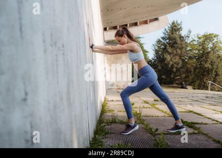Porträt einer jungen Sportlerin in Sportbekleidung vor Betonmauern in der Stadt. Stockfoto