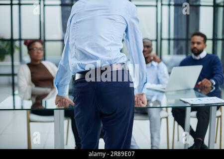 Junger Mitarbeiter, der um Rat von seinen hilfsbereiten, erfahrenen Kollegen im Büro bittet Stockfoto