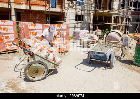 Zrenjanin, Vojvodina, Serbien – 11. Mai 2018: Arbeiter mit Schutzhandschuhen nimmt den Kranhaken von der Schubkarre voller Zellophan, Industriemüll. Stockfoto