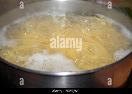 Nudeln kochen in einem Topf mit kochendem Wasser und brennendem Schaum, fast fertig zum Herausnehmen Stockfoto