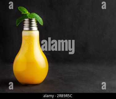 Passionsfruchtsaft und Minze in einem Glühbirnenglas. Schwarzer Hintergrund und Backsteinwand. Stockfoto
