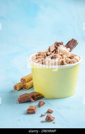 Eisrolle mit Schokolade und Kaffee, mit Schokoladenstückchen und Keksen auf blauem Hintergrund Stockfoto