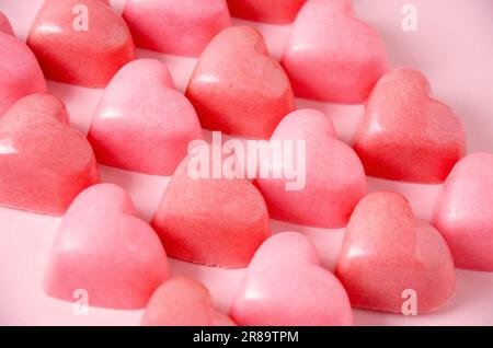 Schokoladenbonbons in Form rosa Herzens. Pinkfarbener, einfarbiger Stockfoto