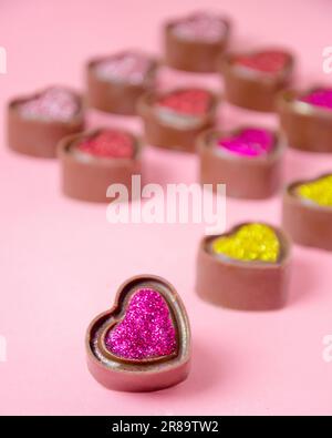 Schokoladenbonbons in Herzform. Pinkfarbener, einfarbiger Stockfoto