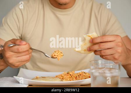 Nahaufnahme eines jungen lateinamerikanischen Mannes, der traditionelle Areas isst. Stockfoto