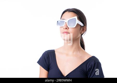 Studioporträt einer jungen braunen Model-Frau, die eine lustige, schicke weiße Sonnenbrille trägt Stockfoto