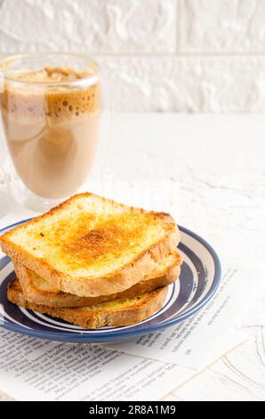 Scheiben getoastetes Brot mit Butter und Kaffee mit Milch. Weißer Hintergrund. Stockfoto